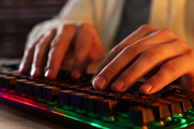 Photo of Young man using computer keyboard at wooden table indoors, closeup