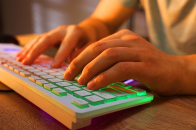 Photo of Young man using computer keyboard at wooden table indoors, closeup