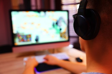 Photo of Young man playing video game at table indoors, closeup. Space for text