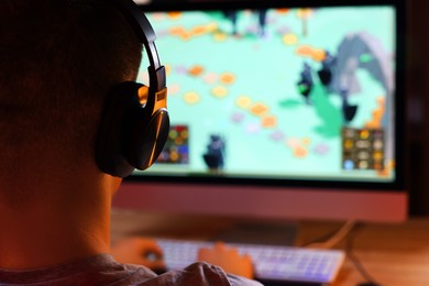 Photo of Young man playing video game at table indoors, closeup. Space for text