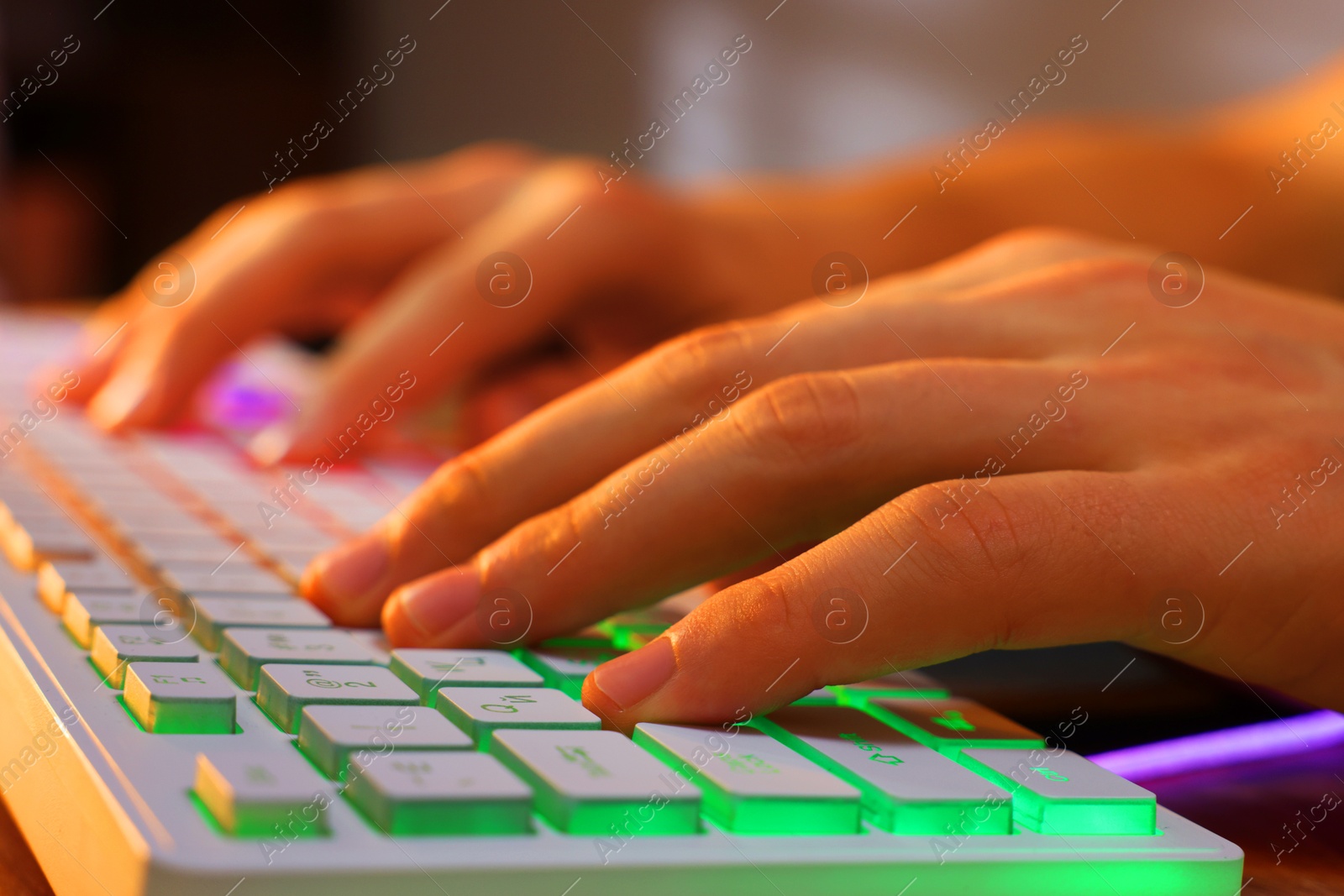 Photo of Young man using computer keyboard at wooden table indoors, closeup