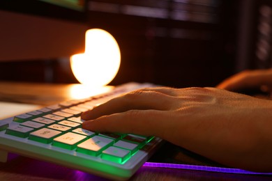 Photo of Young man using computer keyboard at wooden table indoors, closeup