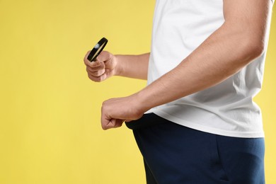 Photo of STD (sexually transmitted diseases). Man examining intimate area with magnifying glass on yellow background, closeup