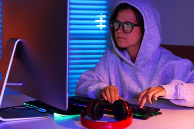 Photo of Woman playing video game with keyboard at table indoors