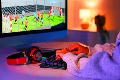 Photo of Woman playing video game with keyboard at table indoors, closeup