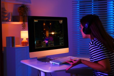 Photo of Woman playing video game with keyboard at table indoors