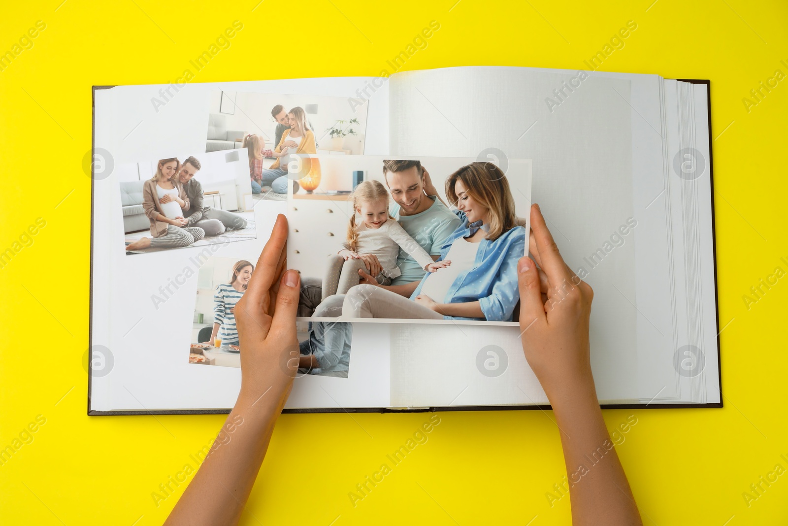 Photo of Woman with open photo album and different photos on yellow background, top view