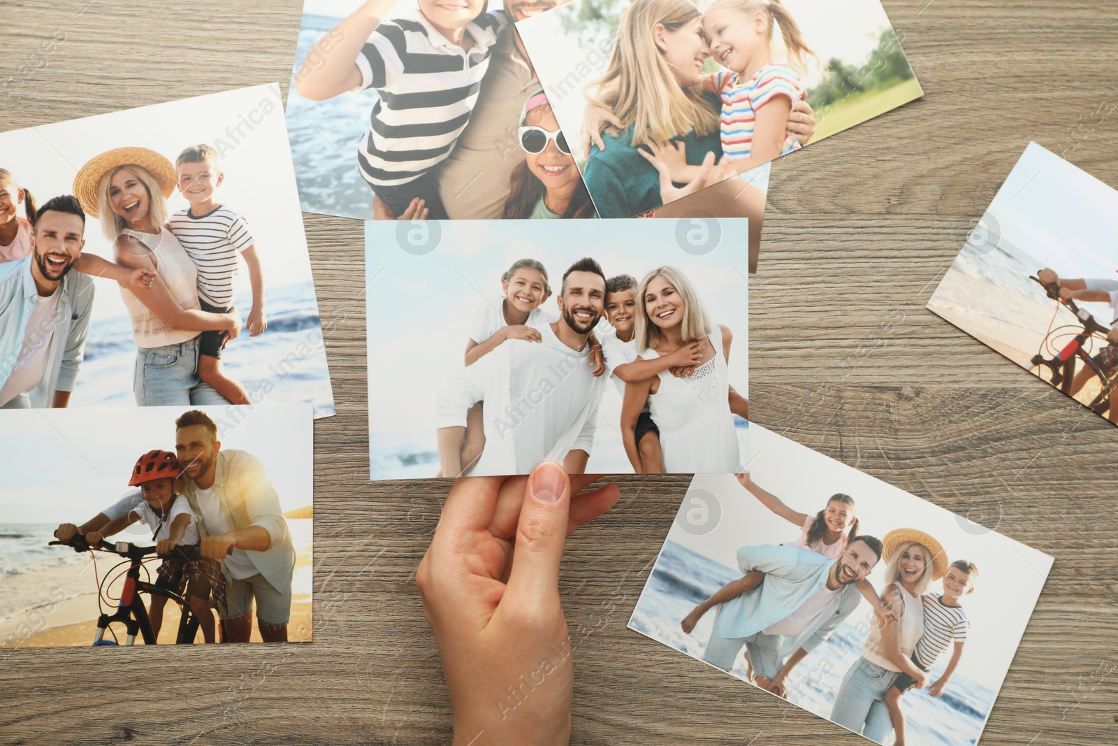 Photo of Woman with different photos at wooden table, top view