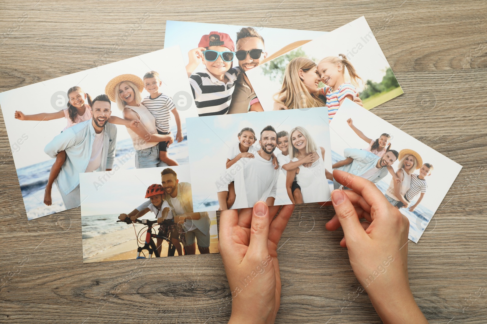 Photo of Woman with different photos at wooden table, top view