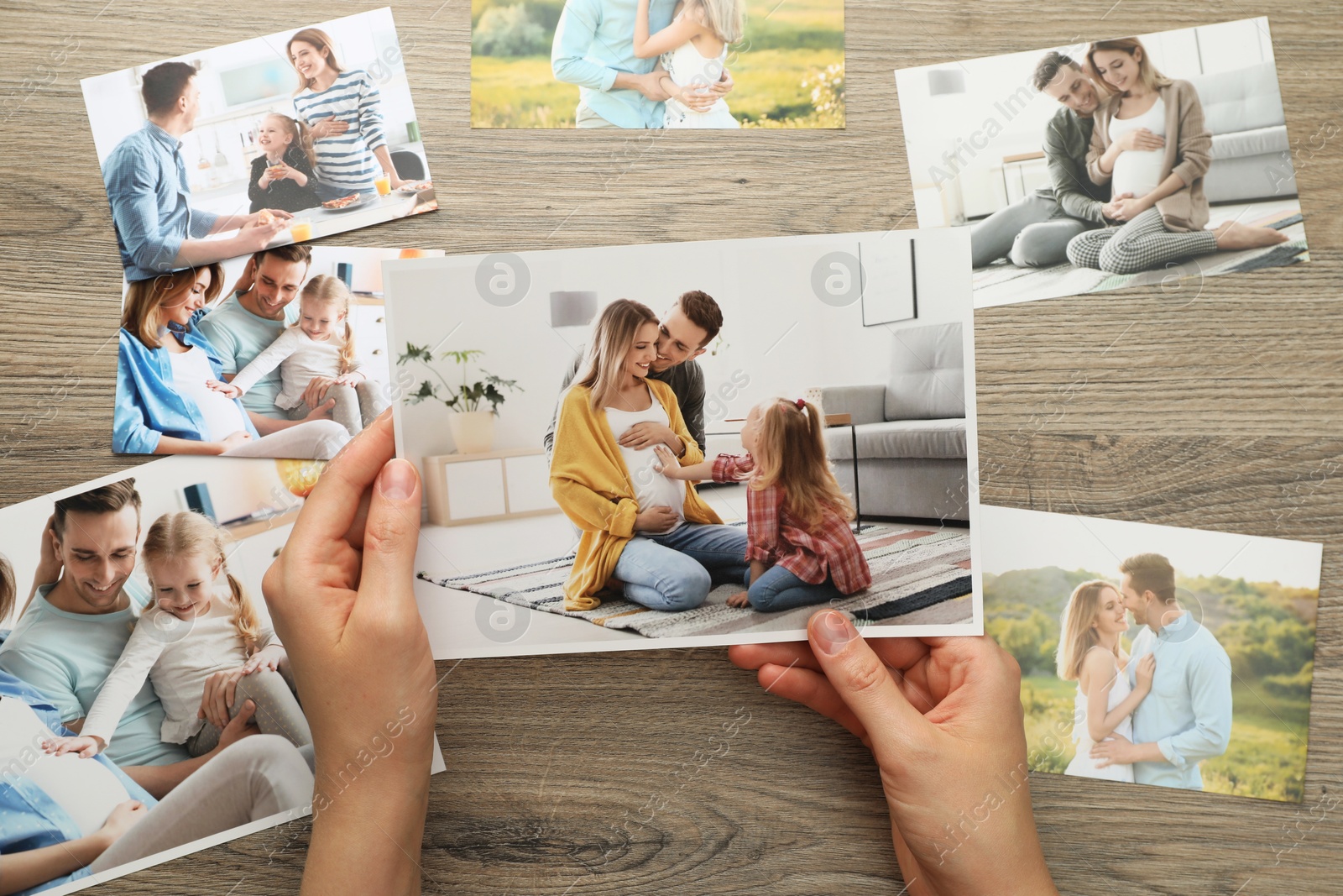 Photo of Woman with different photos at wooden table, top view