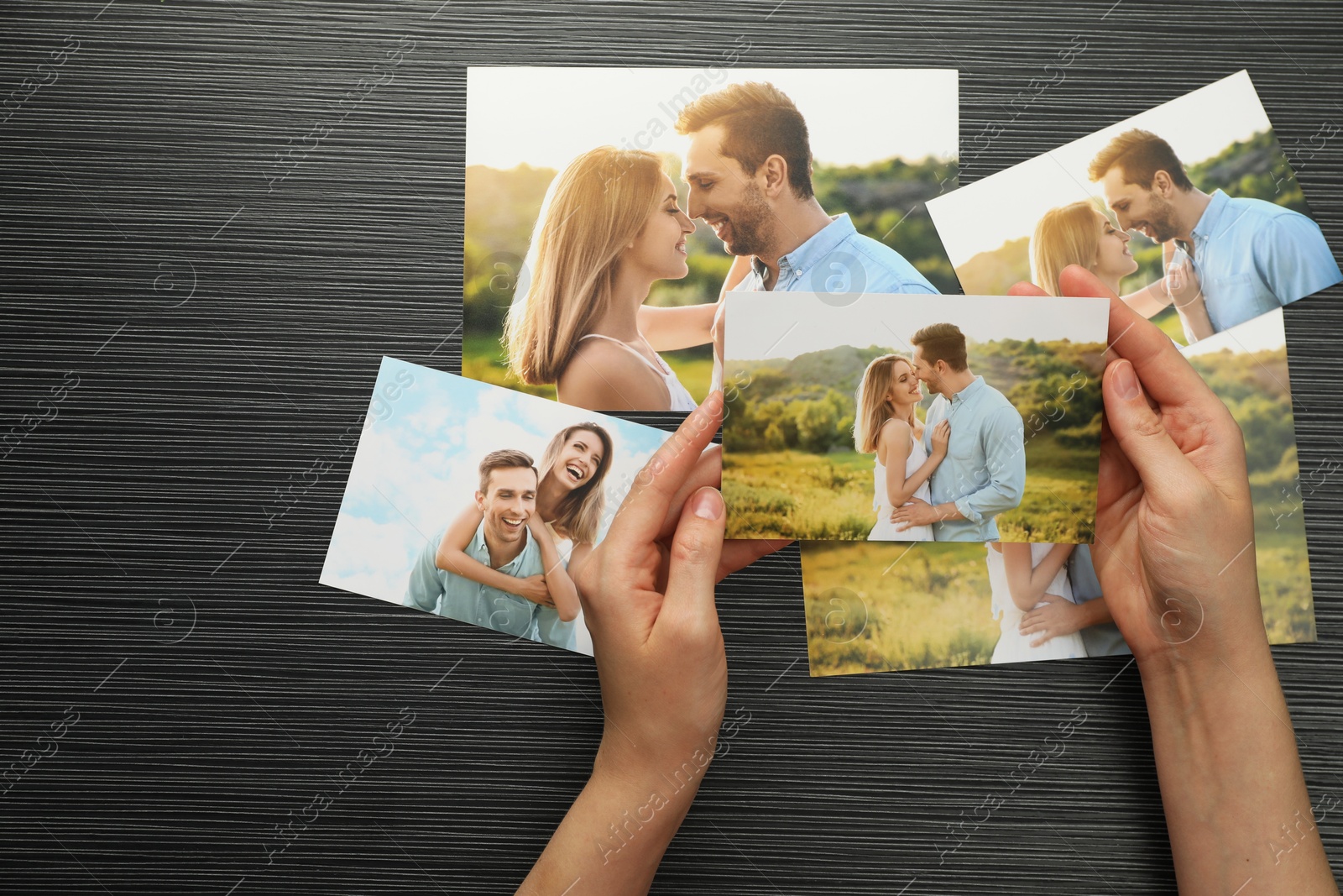 Photo of Woman with different photos at black wooden table, top view