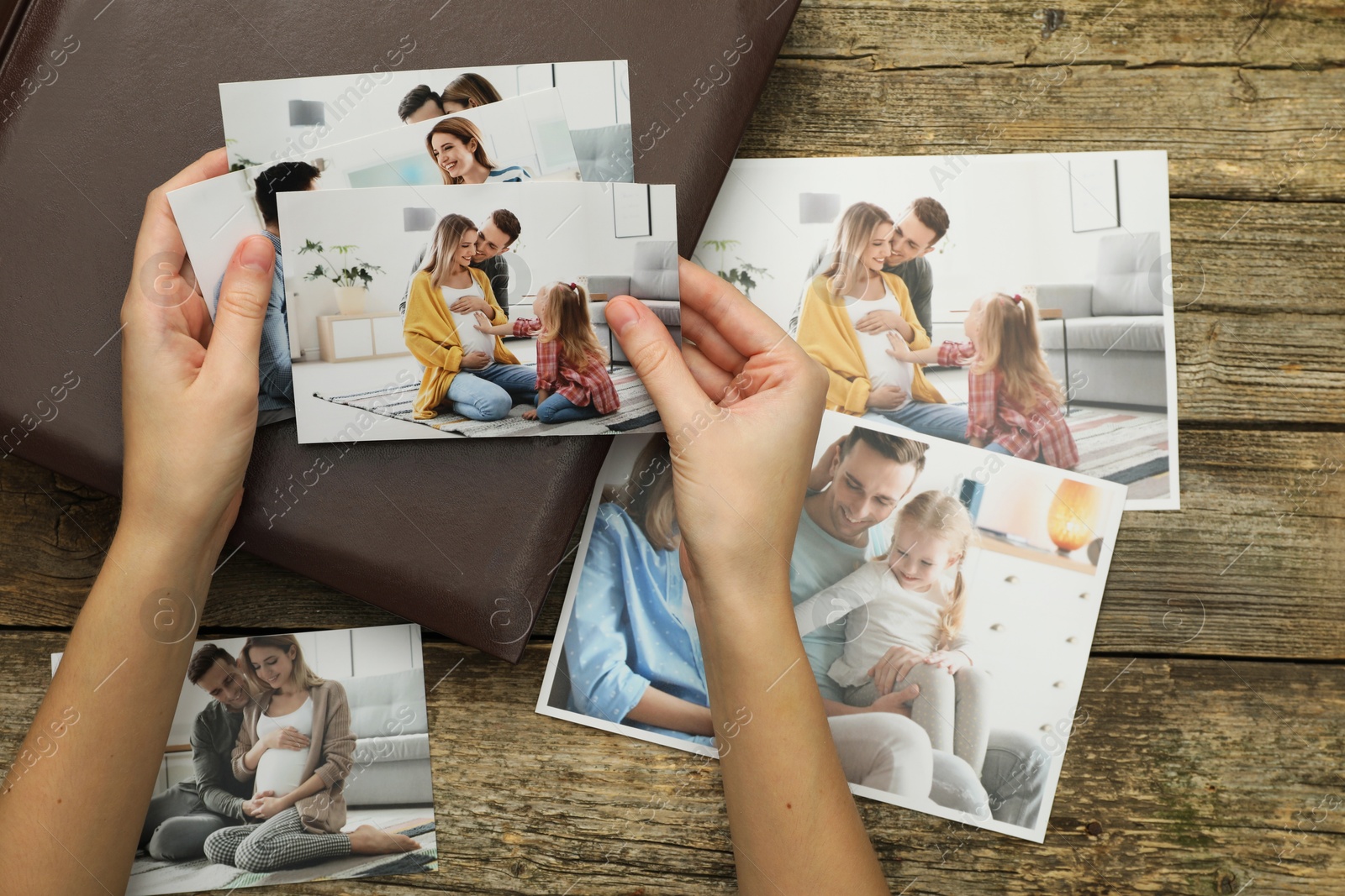 Photo of Woman with different photos and photo album at wooden table, top view