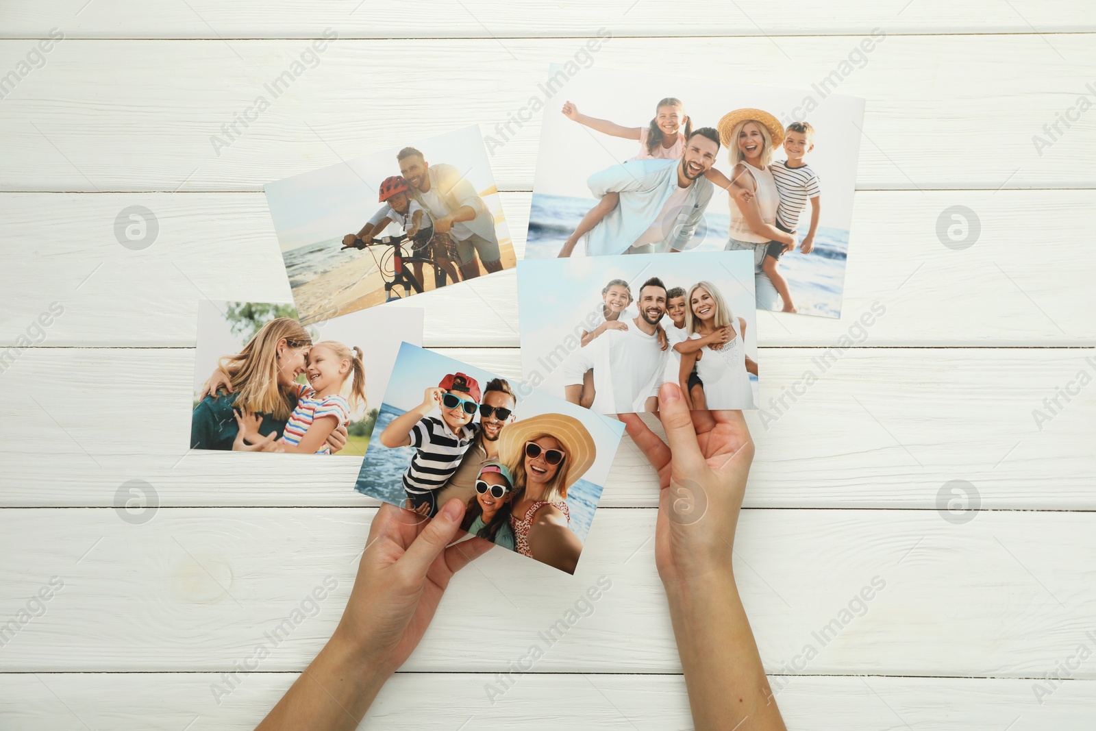 Photo of Woman with different photos at white wooden table, top view