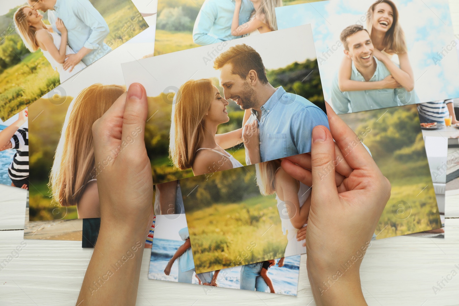 Photo of Woman with different photos at white wooden table, top view