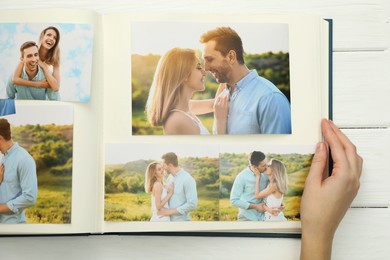 Photo of Woman with different photos in open photo album at white wooden table, top view