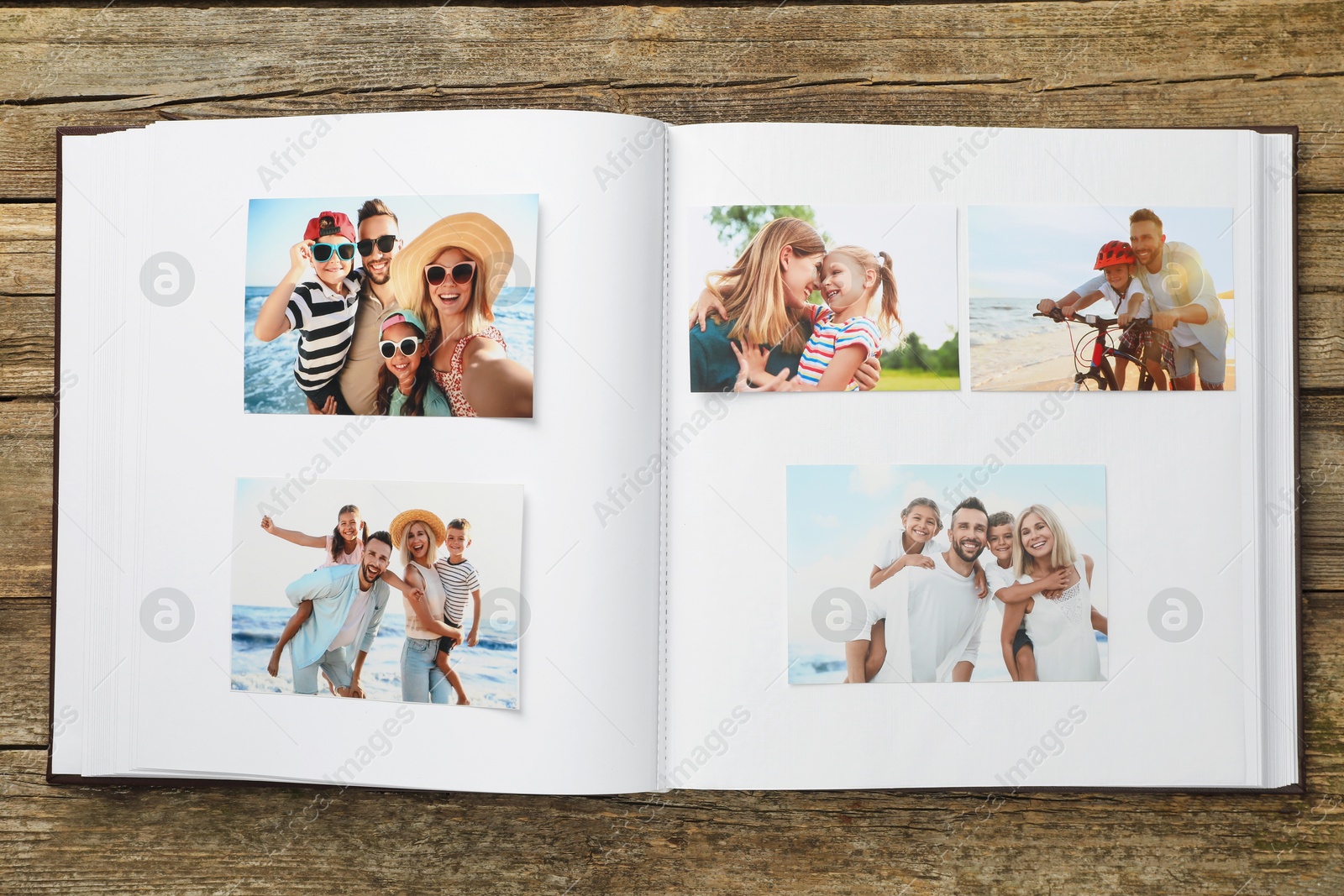 Photo of Different photos in open photo album on wooden table, top view