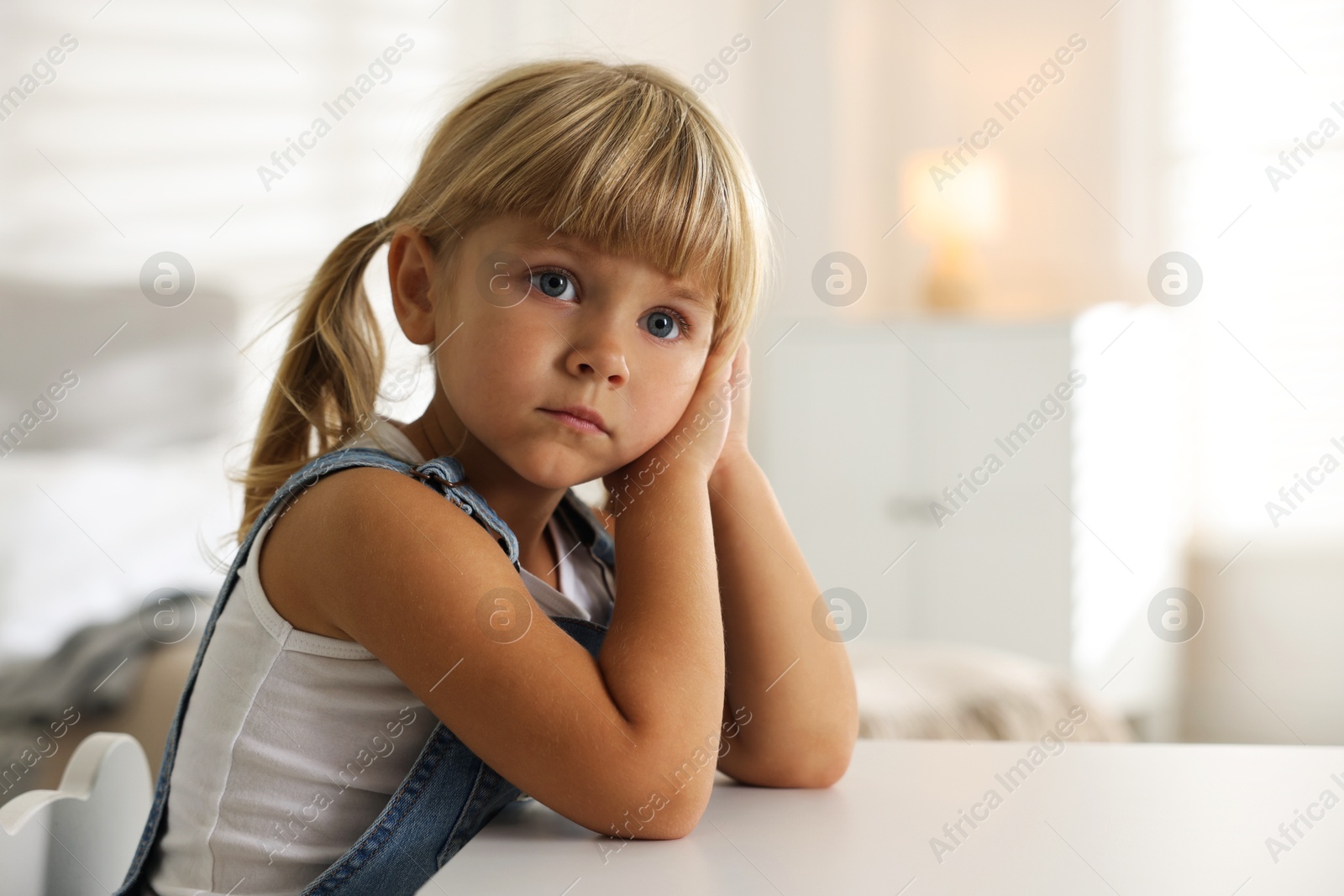 Photo of Orphanage concept. Sad little girl at table indoors, space for text