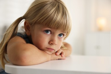 Photo of Orphanage concept. Sad little girl at table indoors, space for text