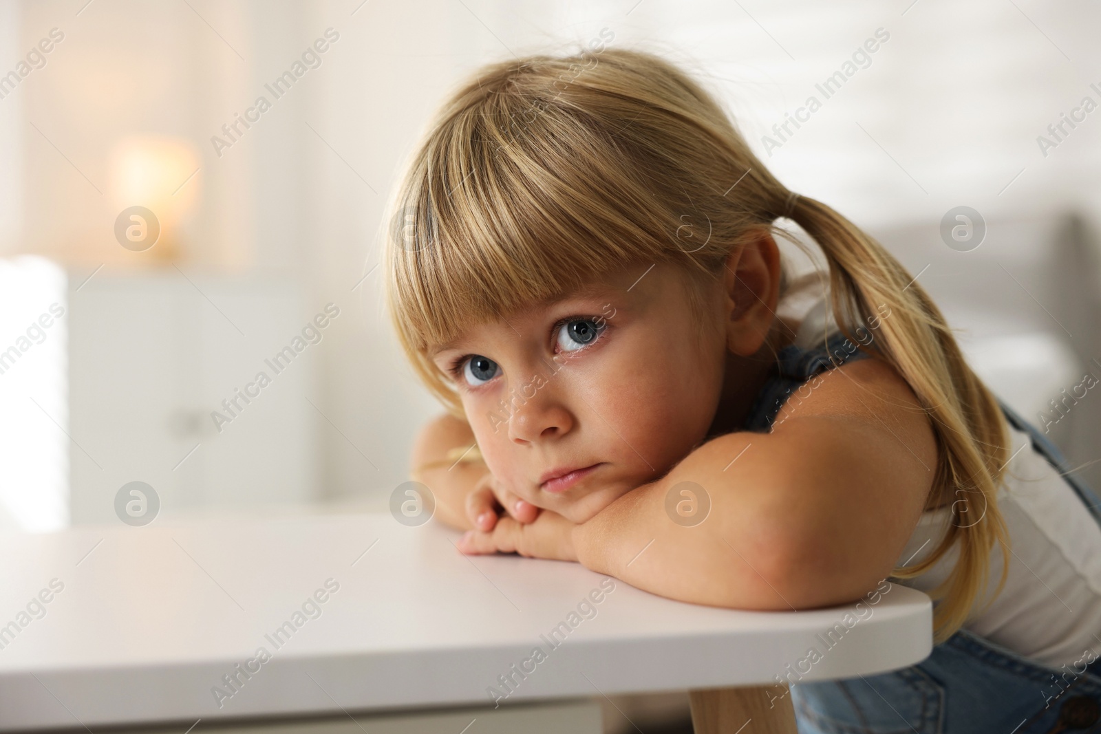 Photo of Orphanage concept. Sad little girl at table indoors, space for text