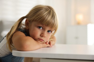 Photo of Orphanage concept. Sad little girl at table indoors, space for text