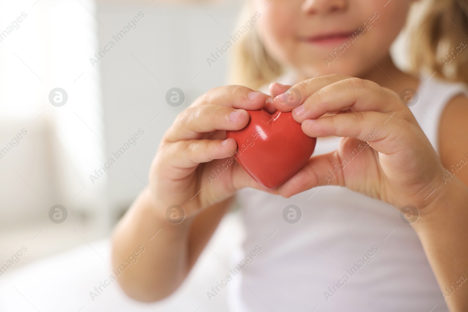 Photo of Orphanage concept. Little girl with red heart figure indoors, closeup