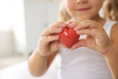 Photo of Orphanage concept. Little girl with red heart figure indoors, closeup