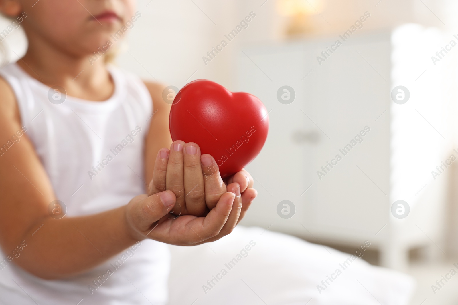 Photo of Orphanage concept. Little girl with red heart figure indoors, closeup. Space for text