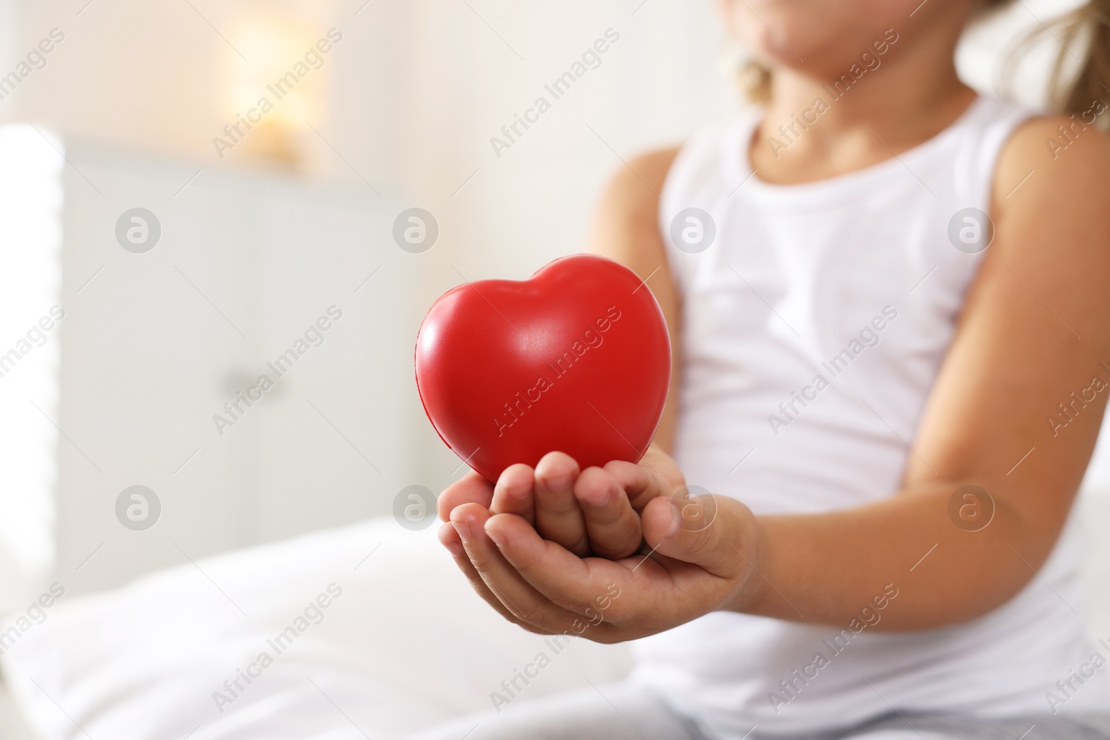 Photo of Orphanage concept. Little girl with red heart figure indoors, closeup