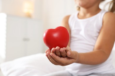 Photo of Orphanage concept. Little girl with red heart figure indoors, closeup