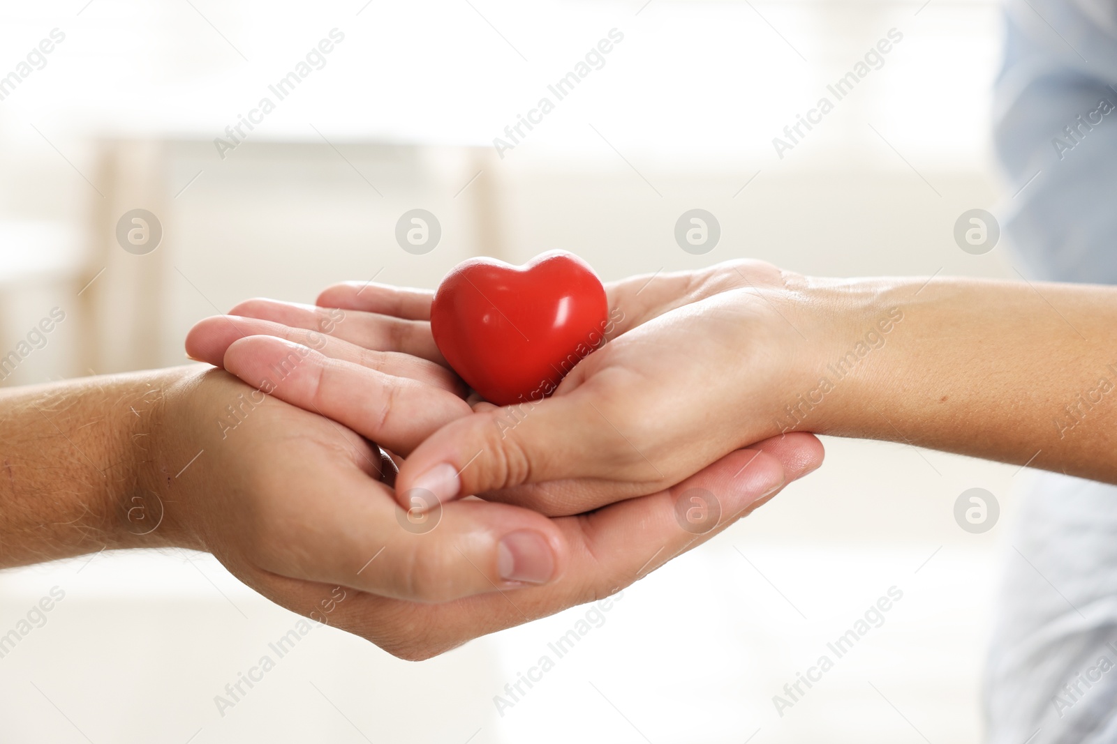 Photo of Little girl and her father with red heart figure indoors, closeup