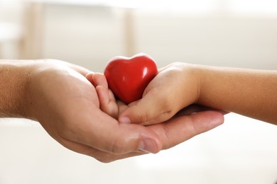 Photo of Little girl and her father with red heart figure indoors, closeup