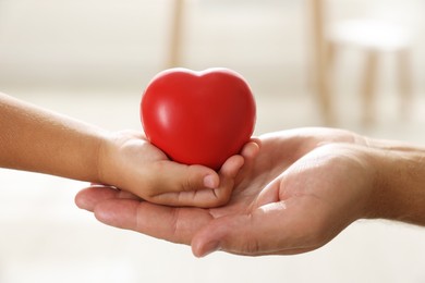 Photo of Little girl and her father with red heart figure indoors, closeup