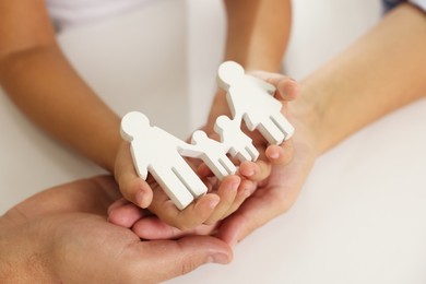 Photo of Parents and child with figures of family at white table, closeup