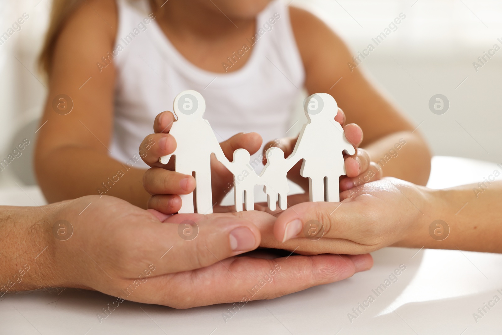 Photo of Parents and child with figures of family at white table, closeup