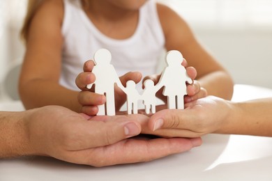 Photo of Parents and child with figures of family at white table, closeup