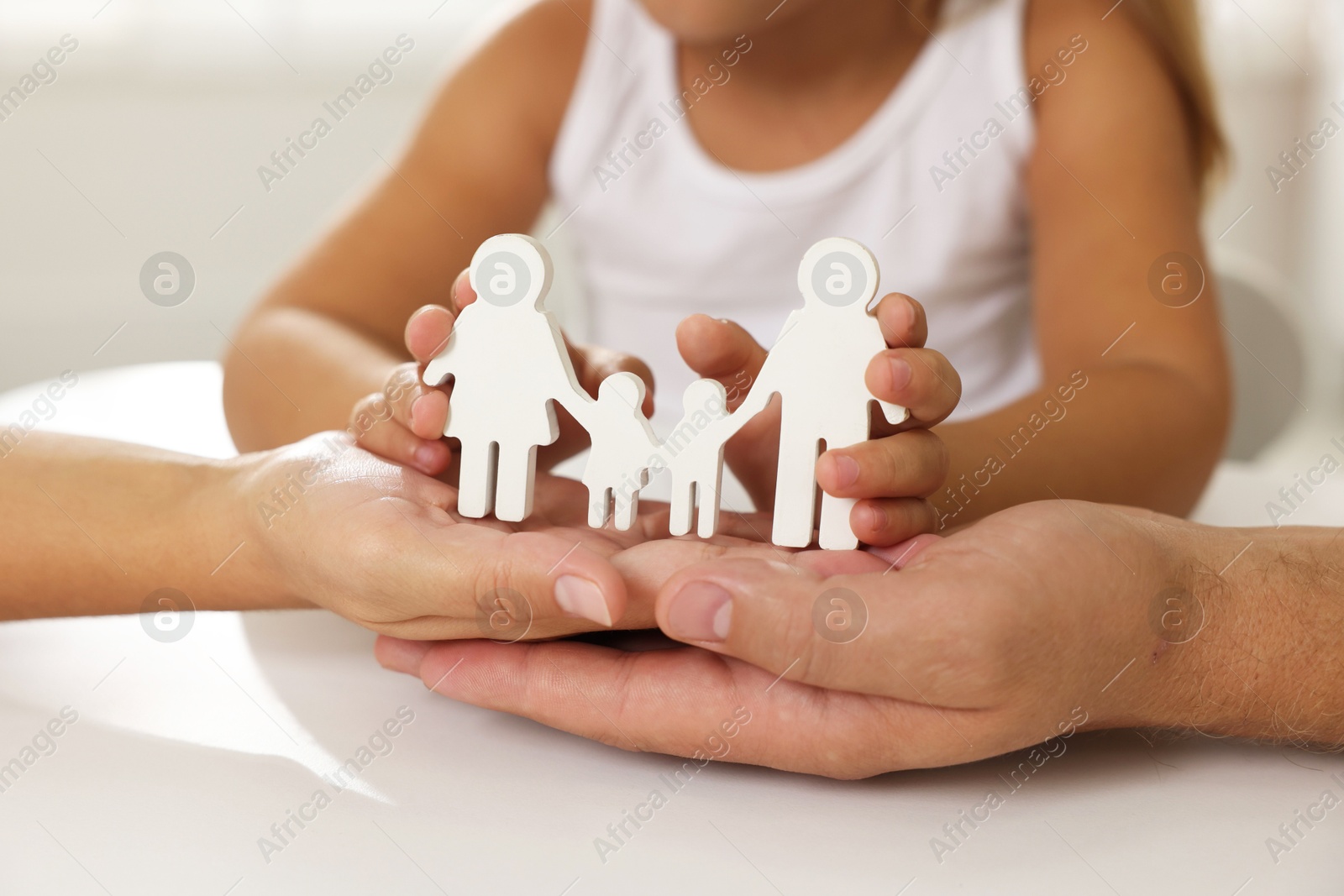 Photo of Parents and child with figures of family at white table, closeup