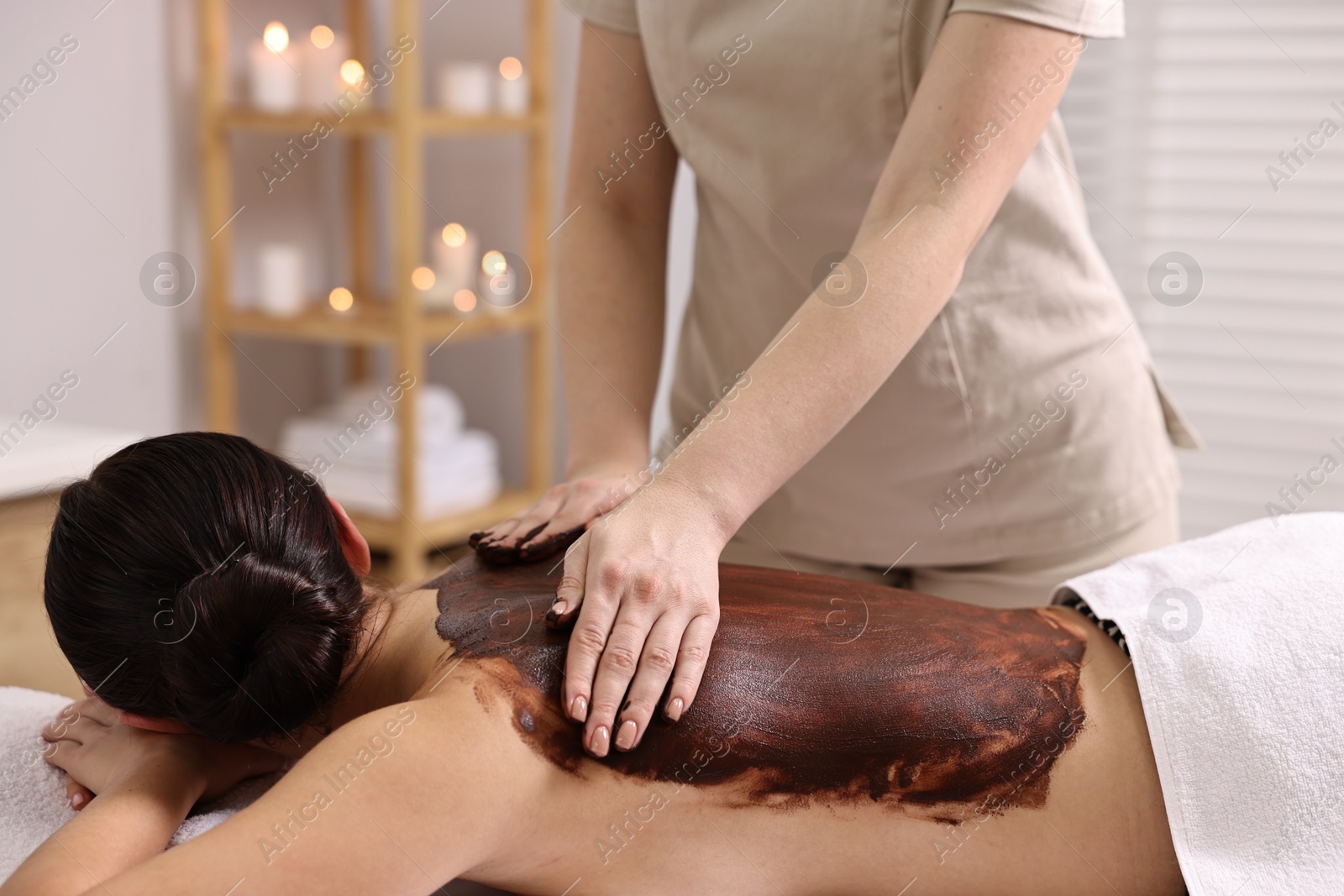 Photo of Woman undergoing chocolate body wrap treatment in spa salon