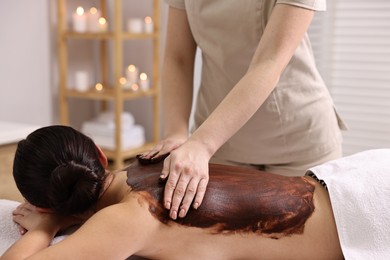 Photo of Woman undergoing chocolate body wrap treatment in spa salon