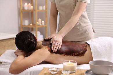 Photo of Woman undergoing chocolate body wrap treatment in spa salon