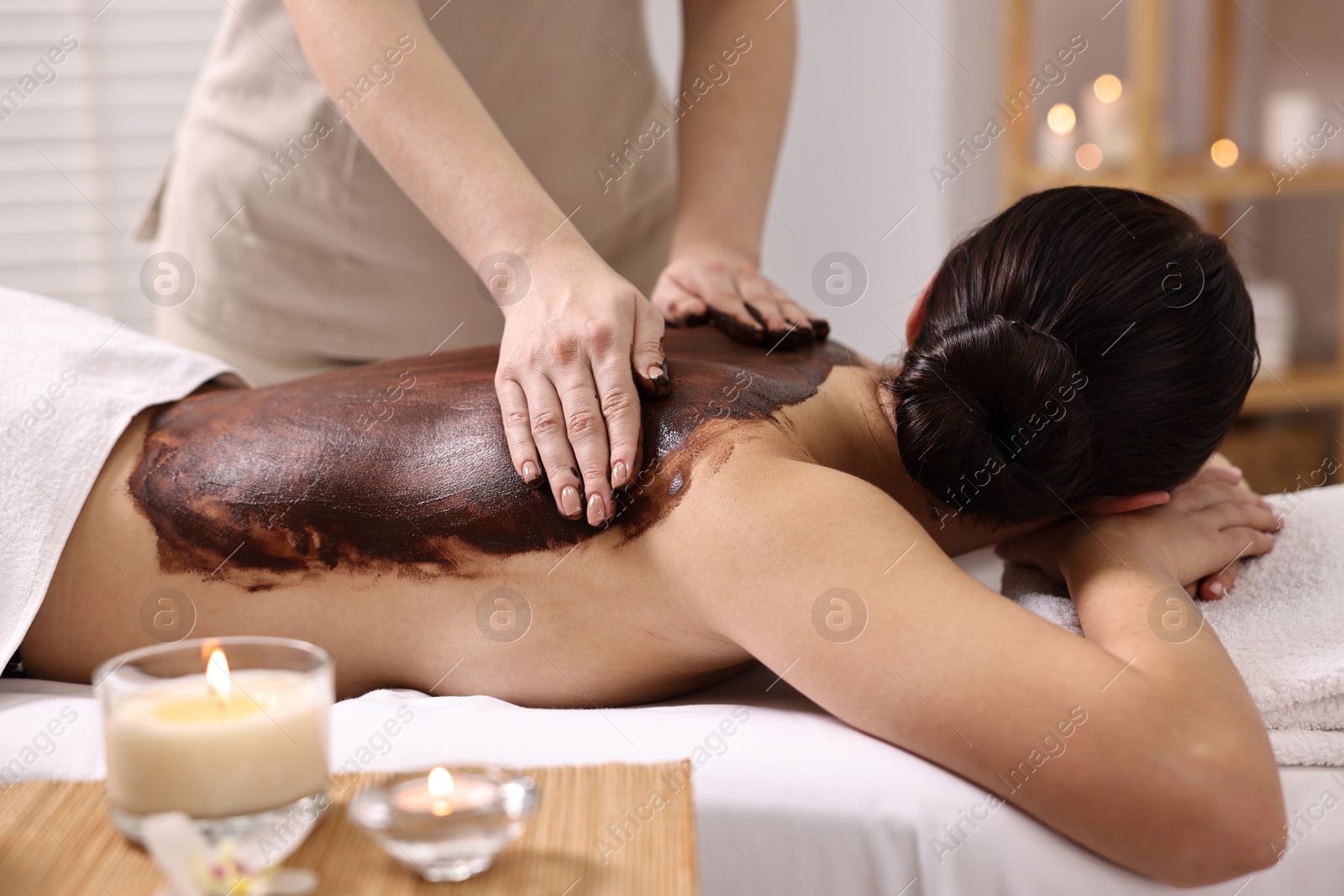 Photo of Woman undergoing chocolate body wrap treatment in spa salon