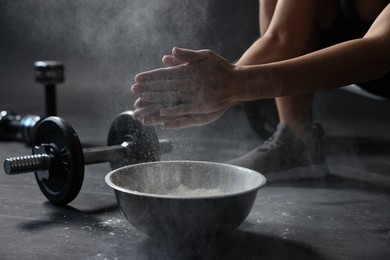 Photo of Woman clapping hands with talcum powder above bowl before training in gym, closeup