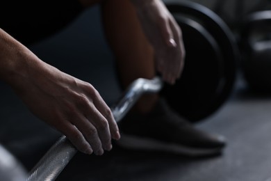 Photo of Woman with talcum powder on hands training with barbell in gym, closeup