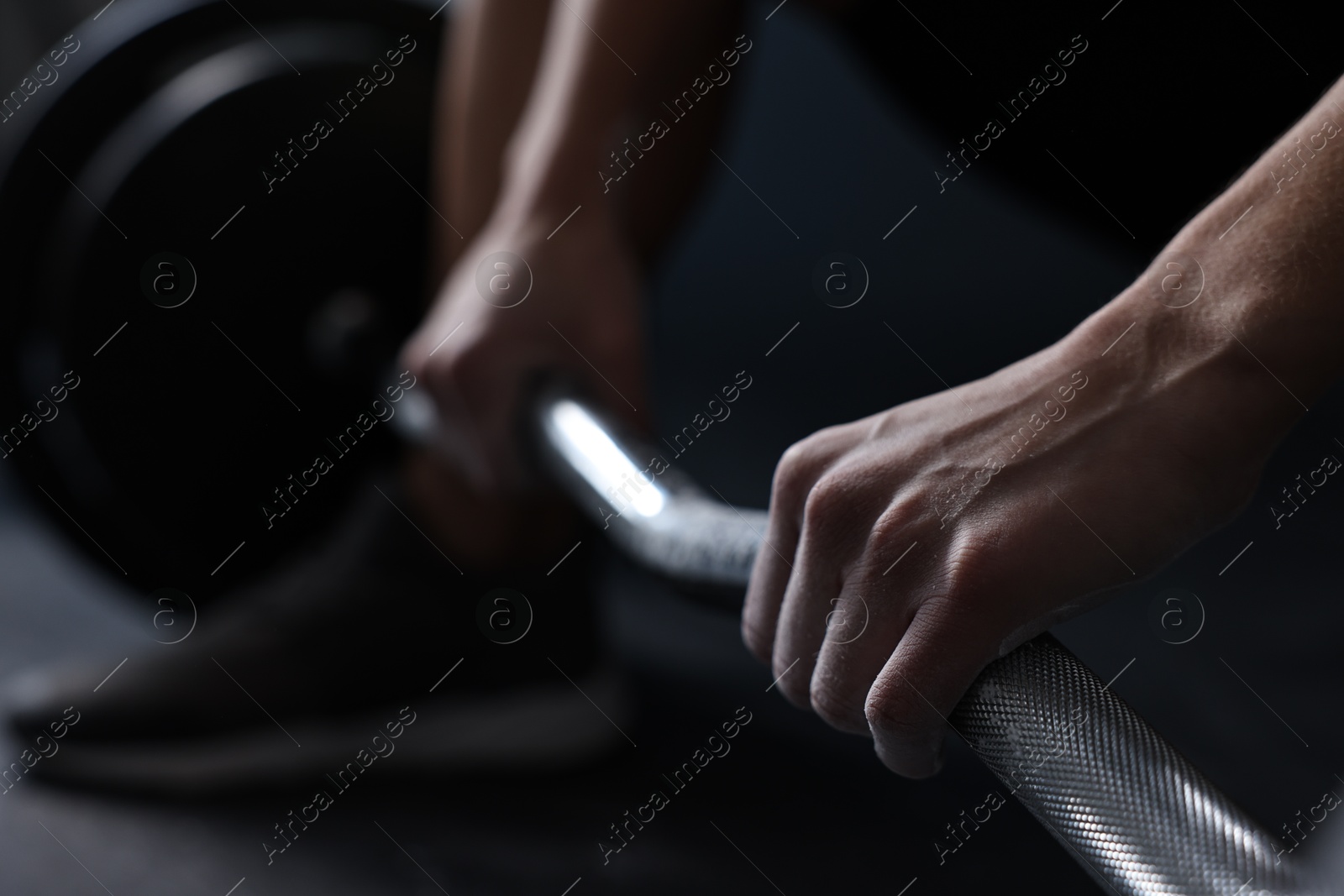 Photo of Woman with talcum powder on hands training with barbell in gym, closeup