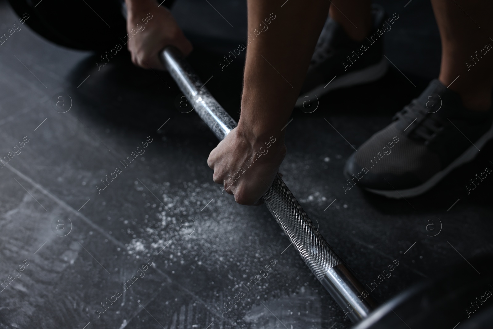 Photo of Woman with talcum powder on hands training with barbell in gym, closeup