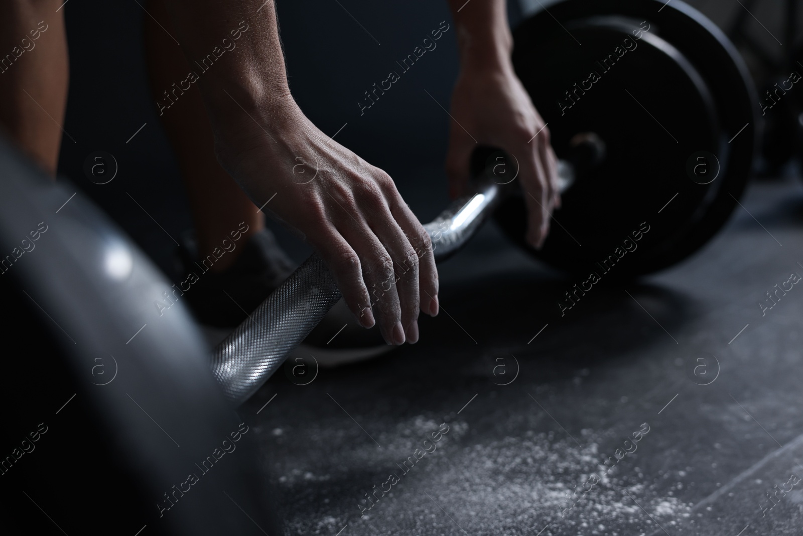 Photo of Woman with talcum powder on hands training with barbell in gym, closeup