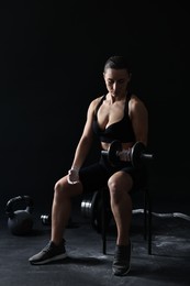 Photo of Woman with talcum powder on hands training with barbell against black background