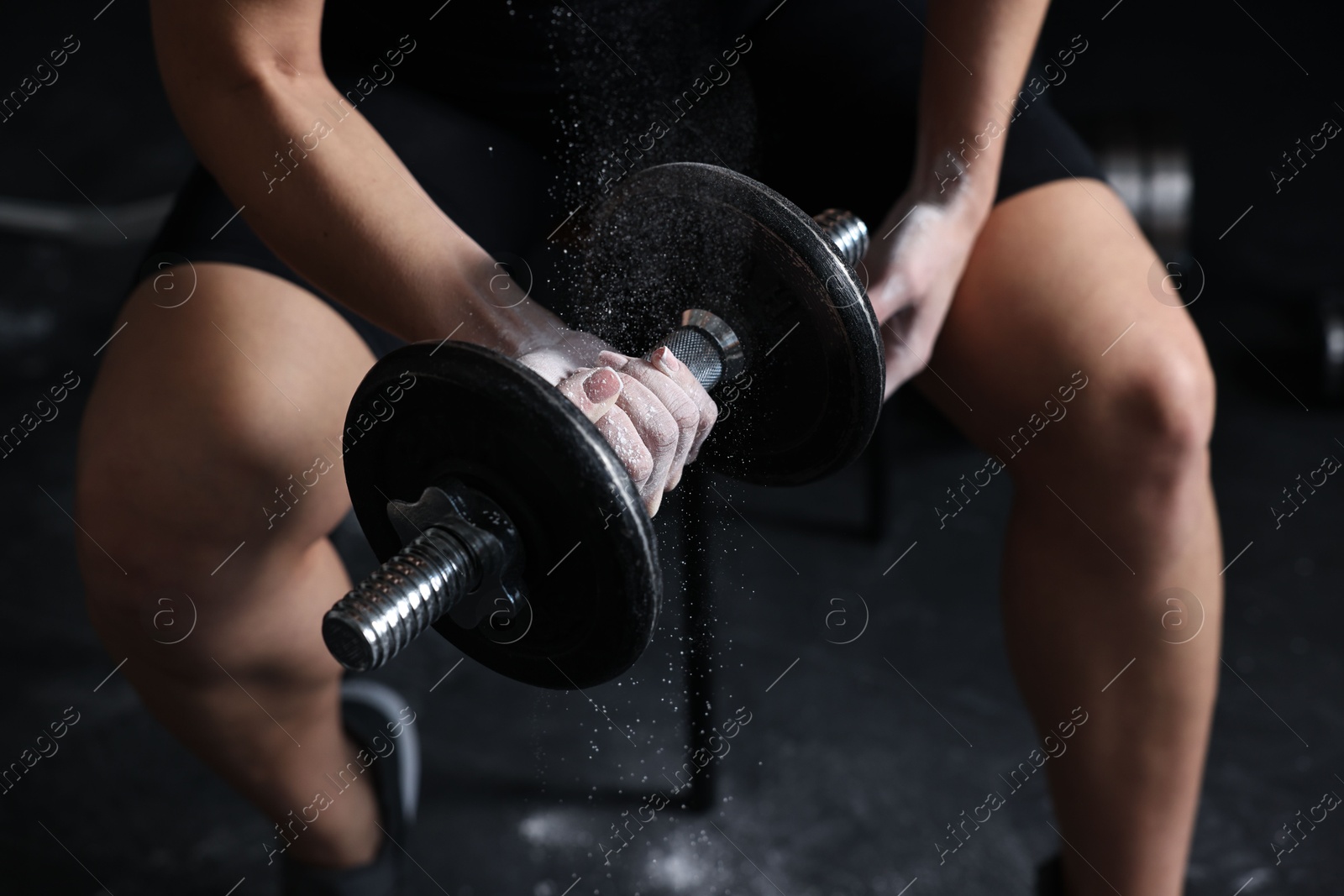 Photo of Woman with talcum powder on hands training with barbell in gym, closeup