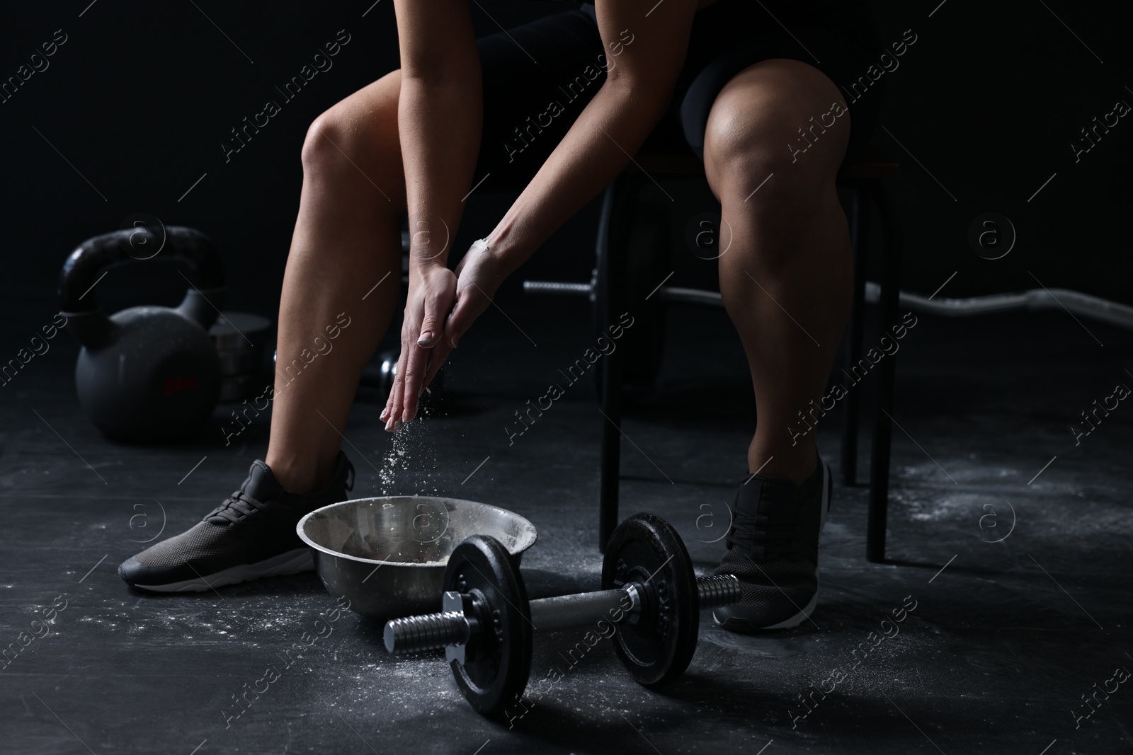 Photo of Woman applying talcum powder onto hands before training in gym, closeup