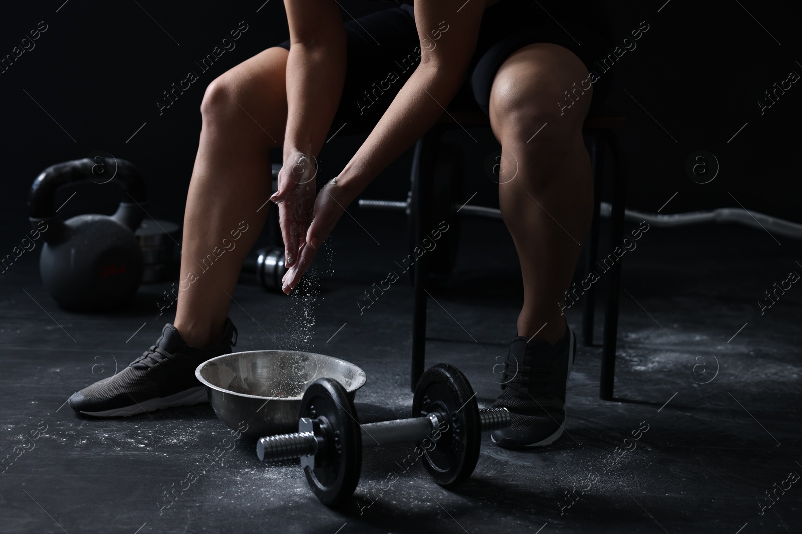 Photo of Woman applying talcum powder onto hands before training in gym, closeup