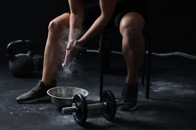 Woman applying talcum powder onto hands before training in gym, closeup